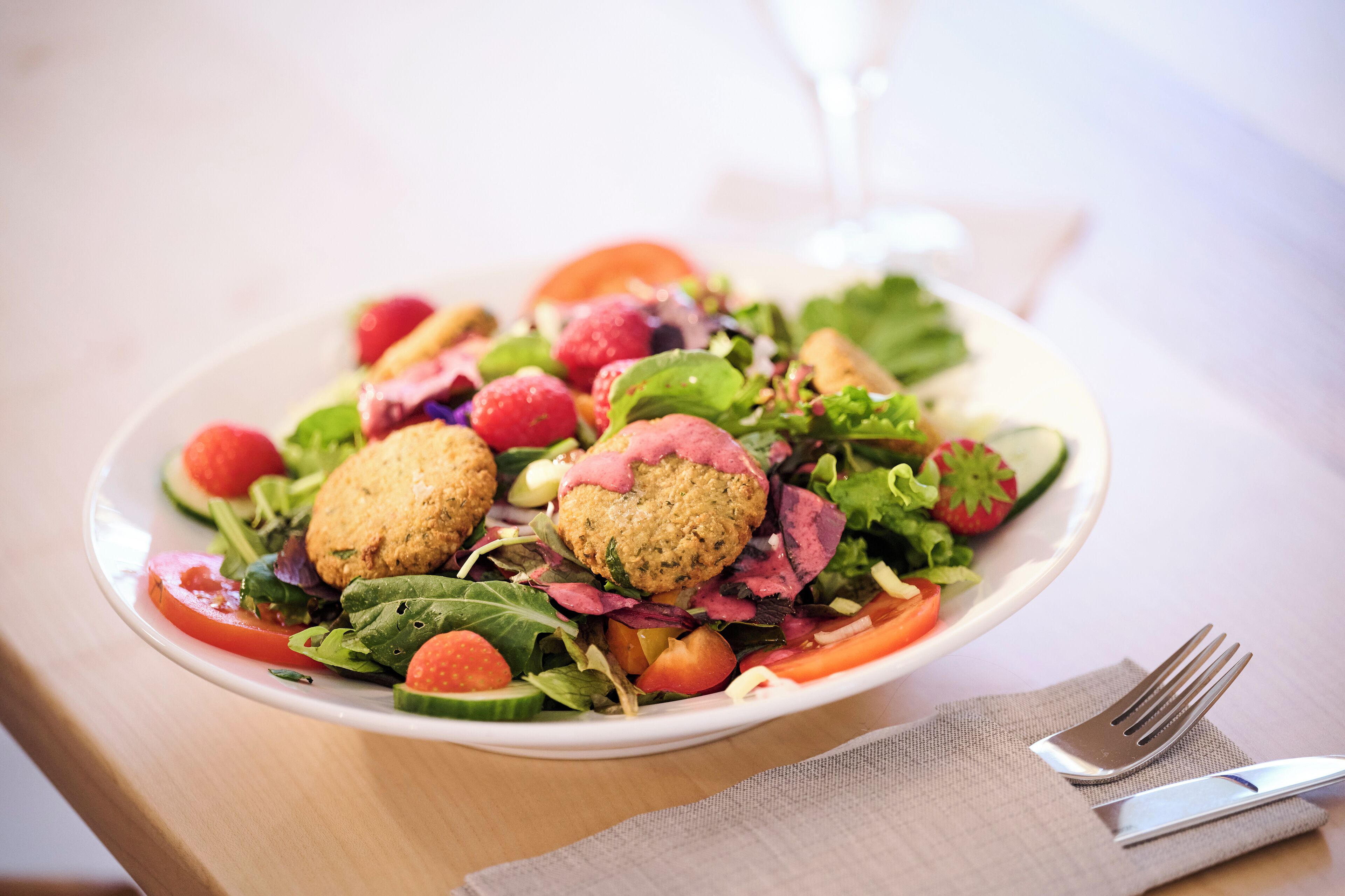 Ein Teller Essen mit Salat, Tomaten und einem Glas Wasser.