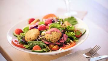 Ein Teller Essen mit Salat, Tomaten und einem Glas Wasser.