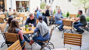 Un café al aire libre con mesas y sillas de madera, rodeado de edificios.
