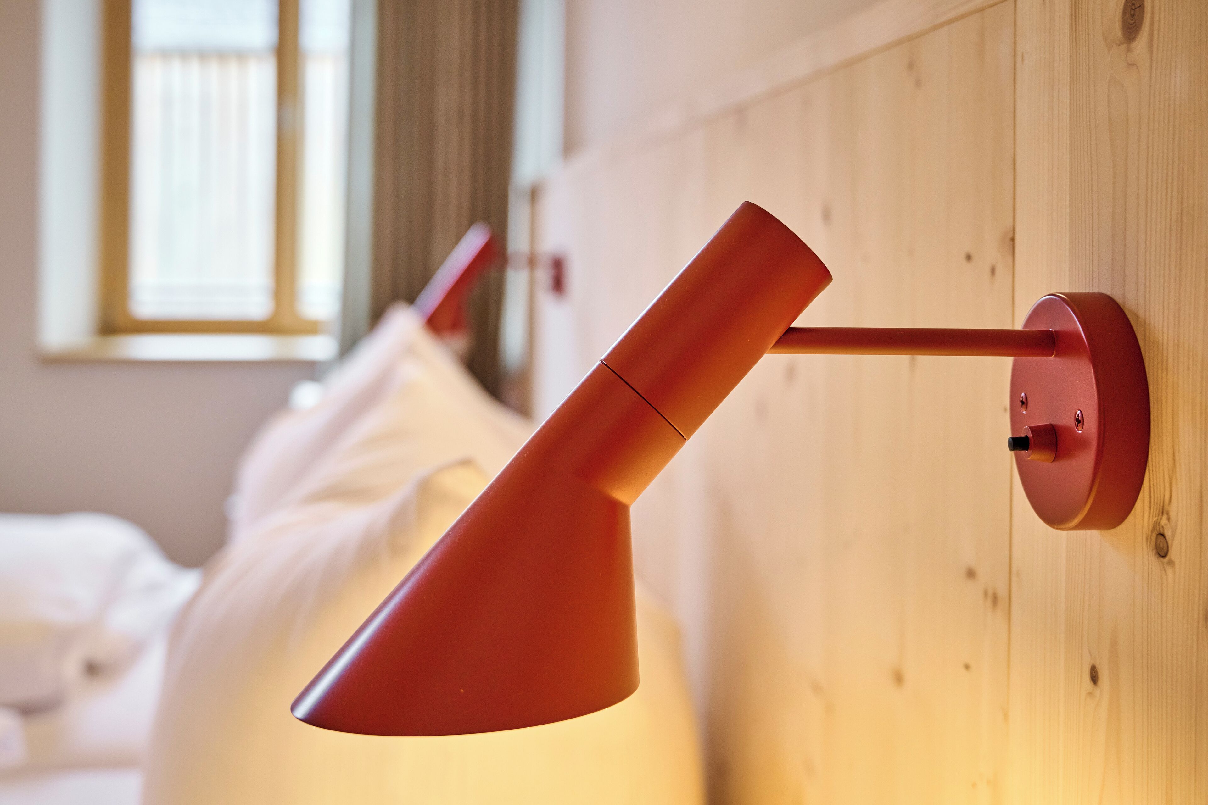 Ein modernes Zimmer mit einer Holzwand und einer roten Wandlampe.