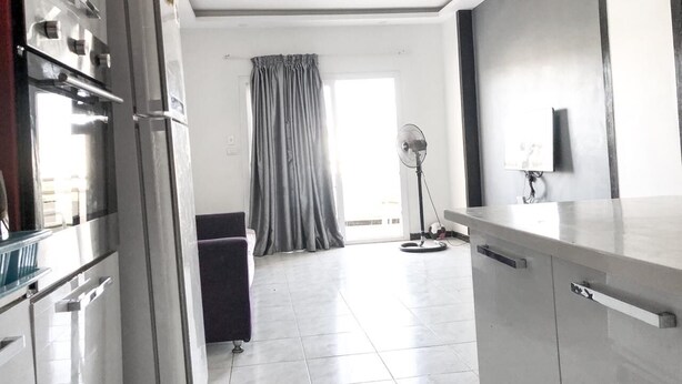 A modern kitchen with stainless steel appliances, a dining area with a table and chairs, and a large window with curtains.