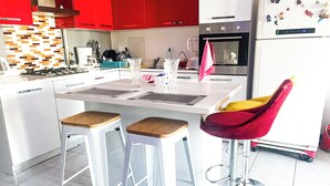 A modern kitchen with white cabinets, a red backsplash, and a stainless steel refrigerator.