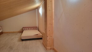 A small, single-bed room with a sloped ceiling and wooden walls. - Cozy apartment near slopes, valley view (La Plagne Montchavin Les Coches)