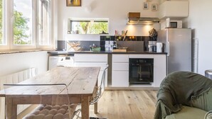 A modern kitchen with a wooden table, a built-in oven, and a refrigerator.