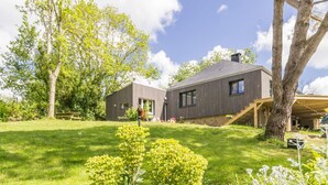 A modern house with a wooden deck and a well-maintained lawn.