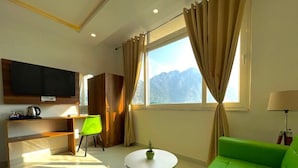 A modern living room with a green sofa, a round coffee table, a TV mounted on the wall, and a window with curtains. - Wanna Stay Rishikesh (Rishikesh)