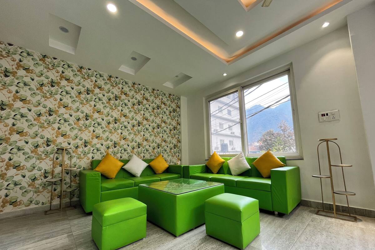 A modern living room with a green sofa set, a coffee table, and a patterned wallpaper.