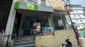 A hotel with a green signboard, a staircase leading to the entrance, and a parked scooter. - Wanna Stay Rishikesh (Rishikesh)