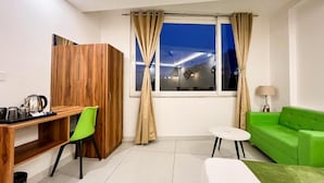 A modern room with a wooden desk, a green chair, a white sofa, and a small table. - Wanna Stay Rishikesh (Rishikesh)