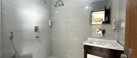 A bathroom with a toilet, a shower, a sink, and a cabinet.
