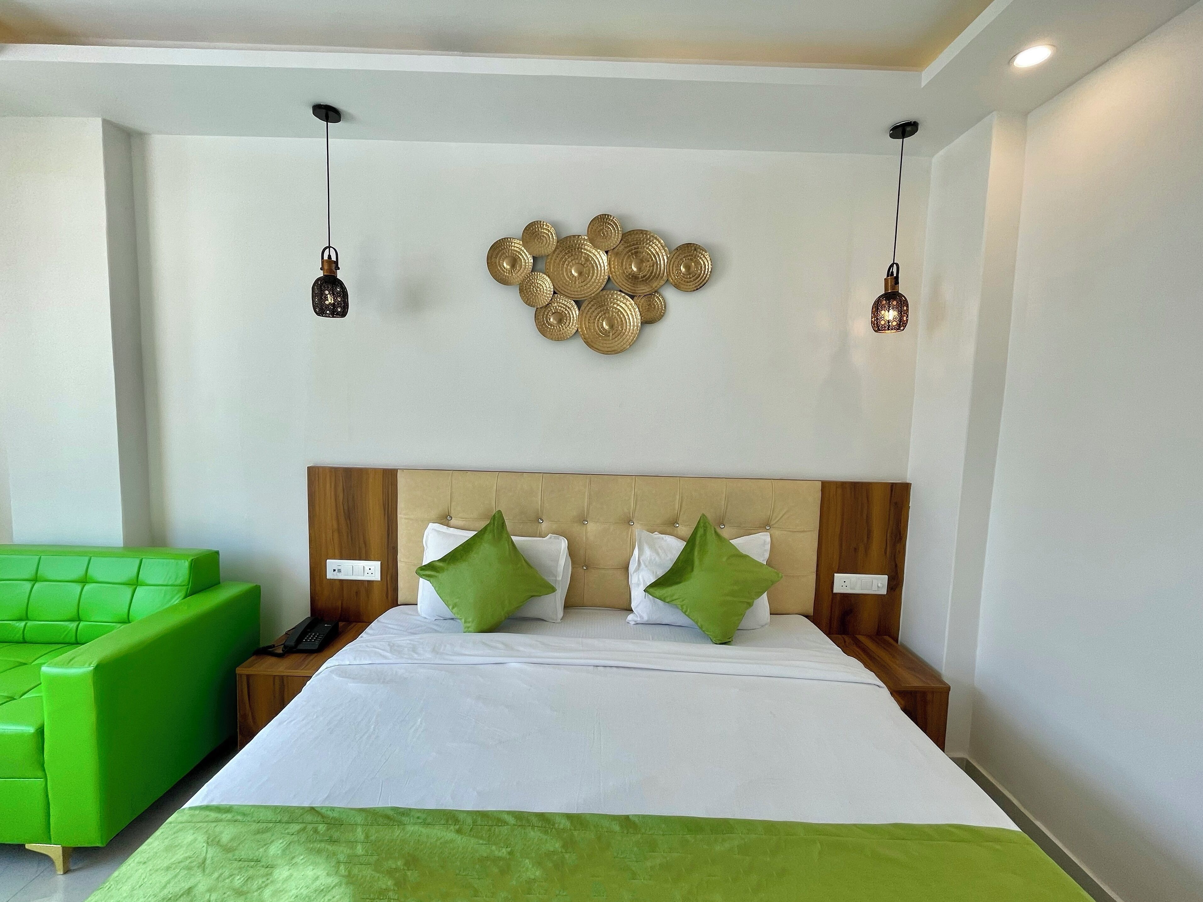 A hotel room with a bed, green couch, and decorative wall art.