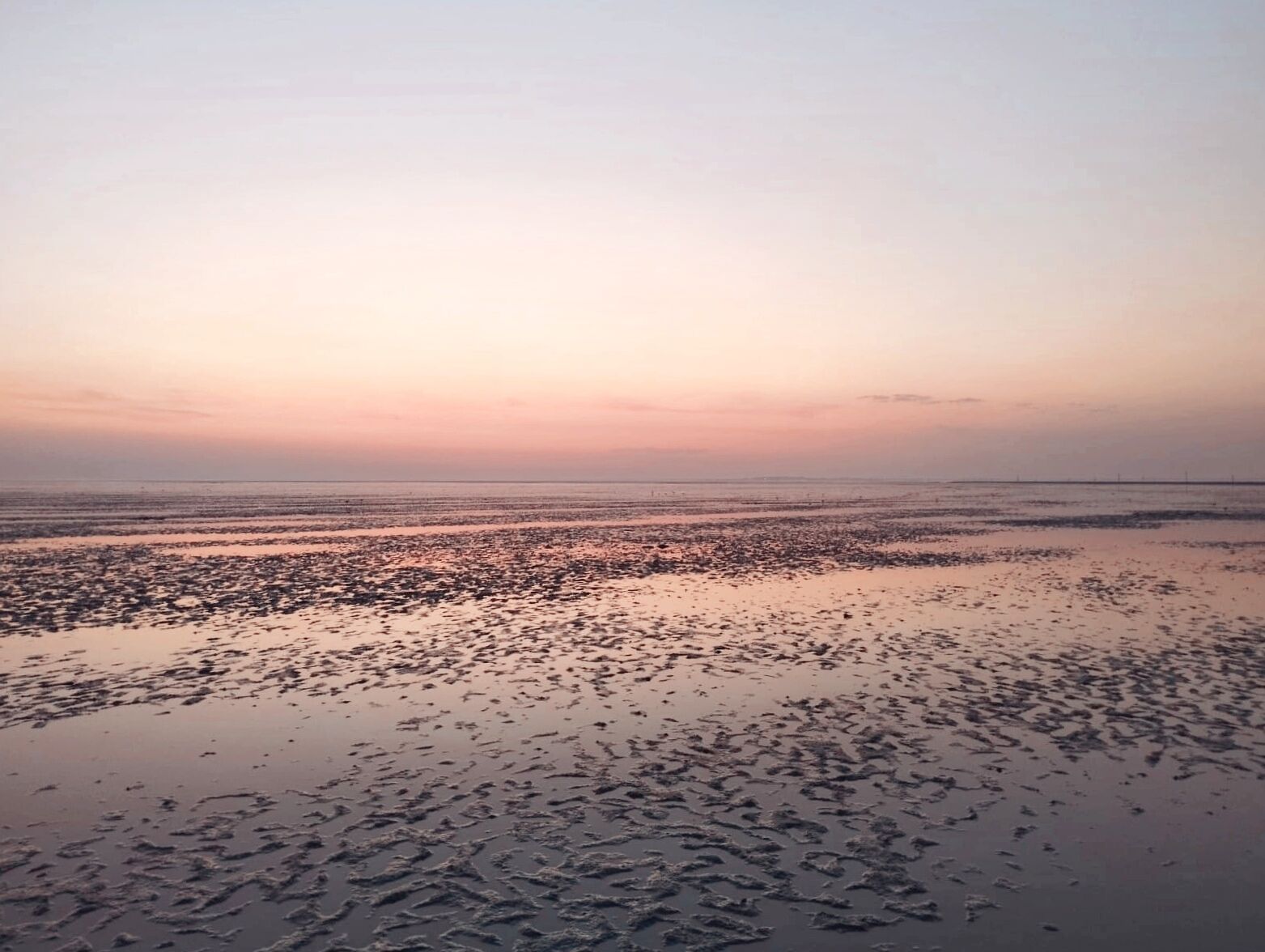 Ein Strand mit ruhigem Meer und blauem Himmel.