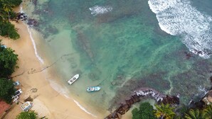 A beach with clear turquoise water, a boat, and a rocky shoreline. - Triton Dondra (Dondra)