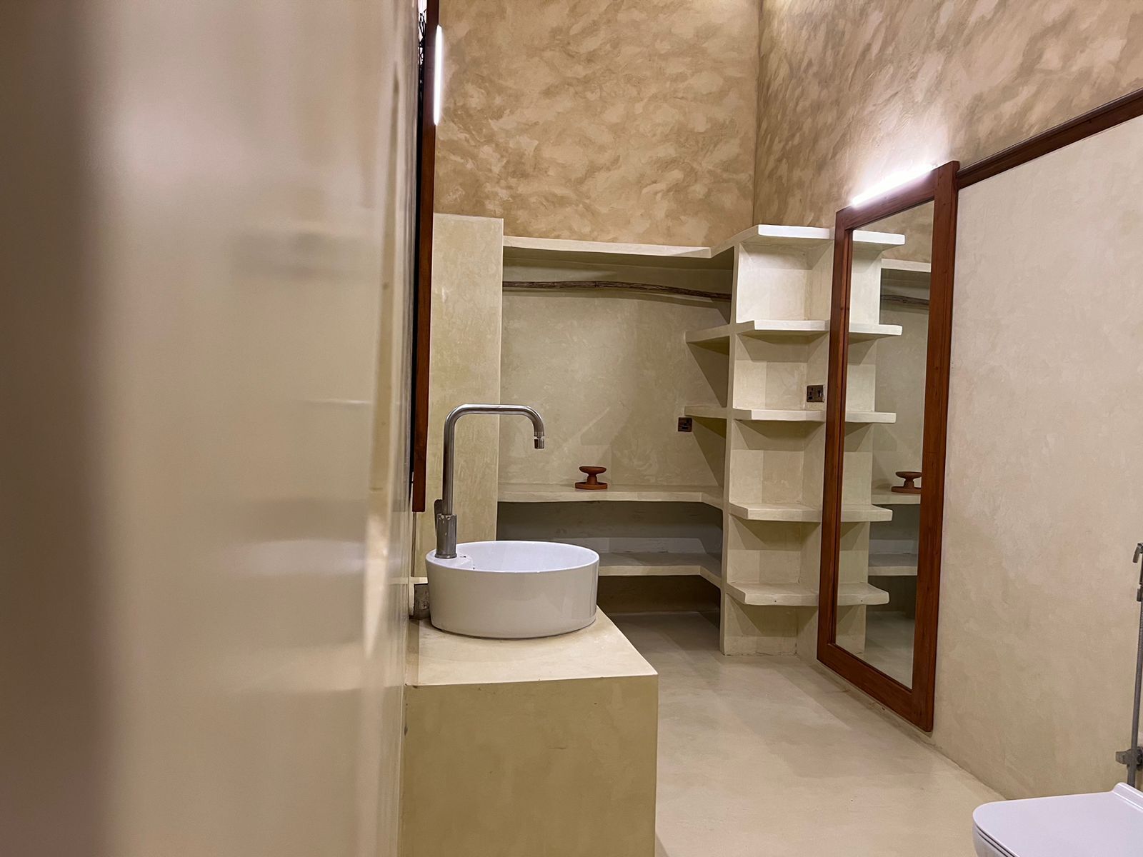 Une salle de bain avec un lavabo blanc, un meuble-lavabo en bois et un miroir.