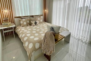 A bedroom with a bed, bedside tables, a laptop on a stand, and sheer curtains. - Apt - Sleeps 4 - Balcony - Pool - Parking (Grand-Baie)