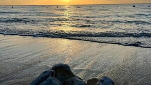 Escena de playa con olas y un atardecer.