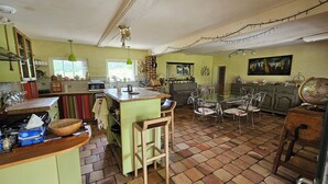 A spacious kitchen with a central island, a dining area with a glass table, and a large globe on a dresser.