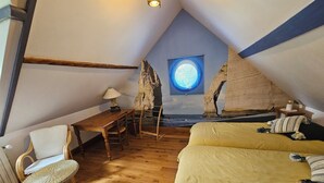 A cozy attic bedroom with a wooden floor, a desk, a chair, and a bed with yellow bedding.