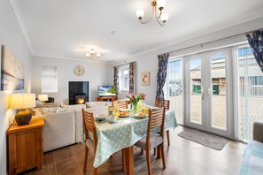 A dining area with a table set for four, a sofa, a TV, and a fireplace. - Chickens, Local Pubs and Country Walks! (Canterbury)