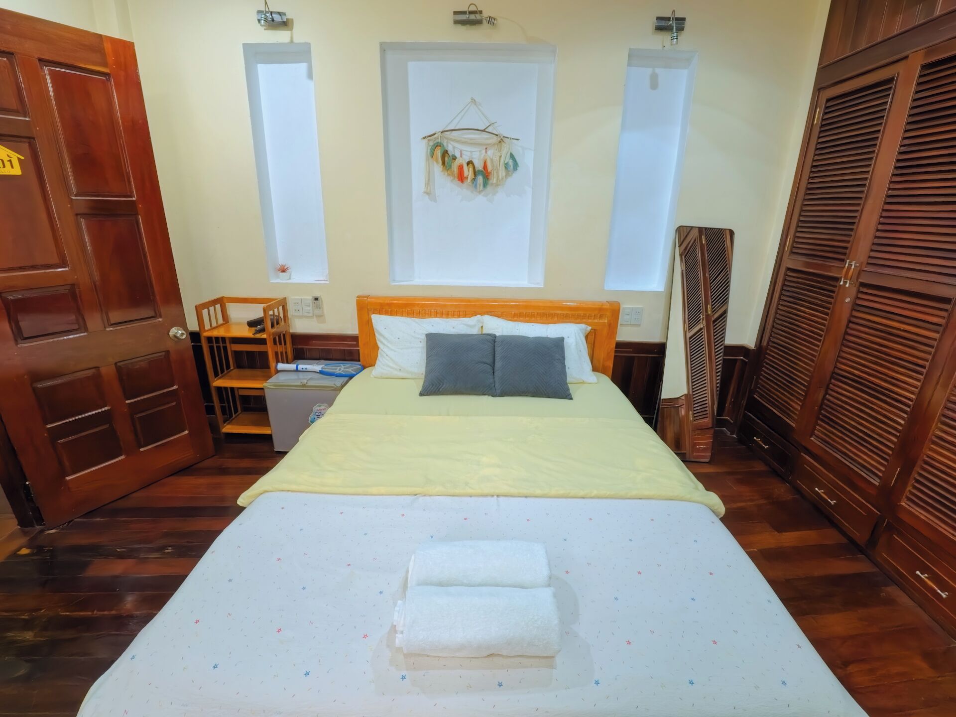 Une chambre d’hôtel comprenant un lit, une table de chevet, une chaise, une fenêtre et une armoire.