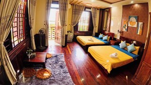 A hotel room with two beds, wooden flooring, a small rug, and a fan. - Canary Homestay (Hue)