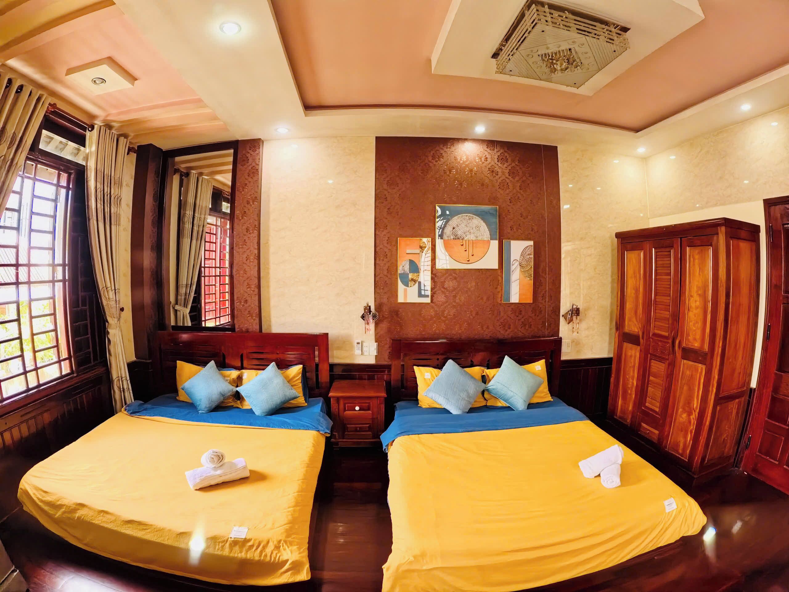 A hotel room with two beds, wooden headboards, and a large wardrobe.