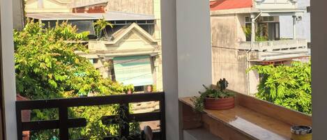 Un balcón con vista a edificios, luces colgantes y plantas en macetas.