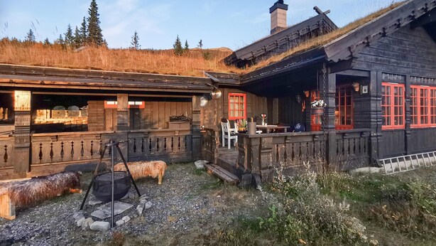 A rustic wooden building with a thatched roof, a wooden fence, and a stone fire pit. - Beautiful home in Rjukan with sauna (Rjukan)