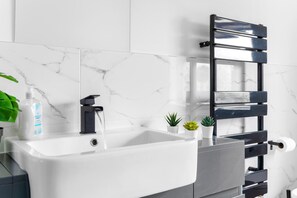 A bathroom with a white sink, a black towel rack, and a bottle of hand soap. - 3br-sleeps8-parking-wifi-closestation (Corby)