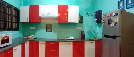 Una cocina con armarios rojos y blancos, un microondas y un refrigerador.