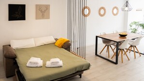 A modern room with a bed, a dining table, and chairs. - Apartamento con terraza y piscina comunitaria en Puerto de la Cruz · 4 pax (Puerto de la Cruz)