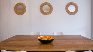 A dining table with a bowl of fruit, surrounded by white chairs, and three wall-mounted mirrors. - Apartamento con terraza y piscina comunitaria en Puerto de la Cruz · 4 pax (Puerto de la Cruz)