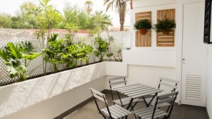 A balcony with a table and chairs, surrounded by plants and a white fence. - Apartamento con terraza y piscina comunitaria en Puerto de la Cruz · 4 pax (Puerto de la Cruz)