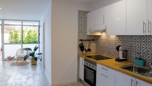 A modern kitchen with white cabinets, a wooden countertop, and a patterned backsplash. - Apartamento con terraza y piscina comunitaria en Puerto de la Cruz · 4 pax (Puerto de la Cruz)