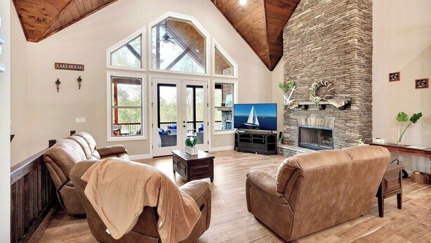 Una sala de estar amplia con chimenea de piedra, sofás de cuero y un televisor grande.