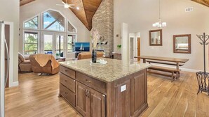 Una cocina amplia con una isla grande, techo de madera y chimenea de piedra.