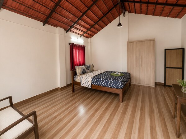 Quarto com cama, uma cadeira, guarda-roupa e teto com telhado vermelho.