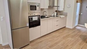 A kitchen with a refrigerator, oven, microwave, sink, and cabinets.