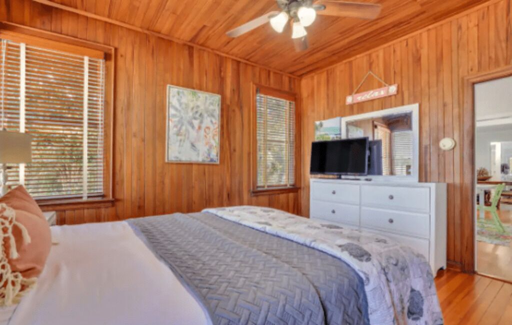 A wooden-paneled bedroom with a bed, a TV, and a dresser.