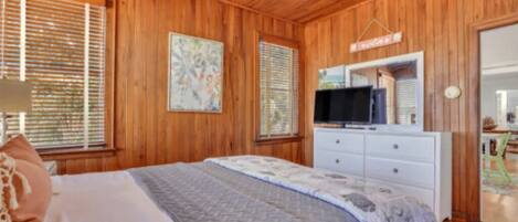 A wooden-paneled bedroom with a bed, a TV, and a dresser.