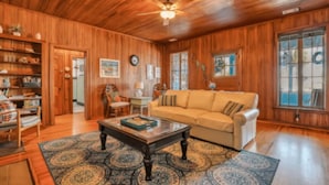 A wooden-paneled room with a sofa, coffee table, and bookshelves. - Seaside Serenity: 3BR/2BA Coastal Retreat
 (Tybee Island)