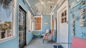 A room with a ceiling fan, a window with decorative ironwork, a chair, and a wall with various items. - Seaside Serenity: 3BR/2BA Coastal Retreat
 (Tybee Island)