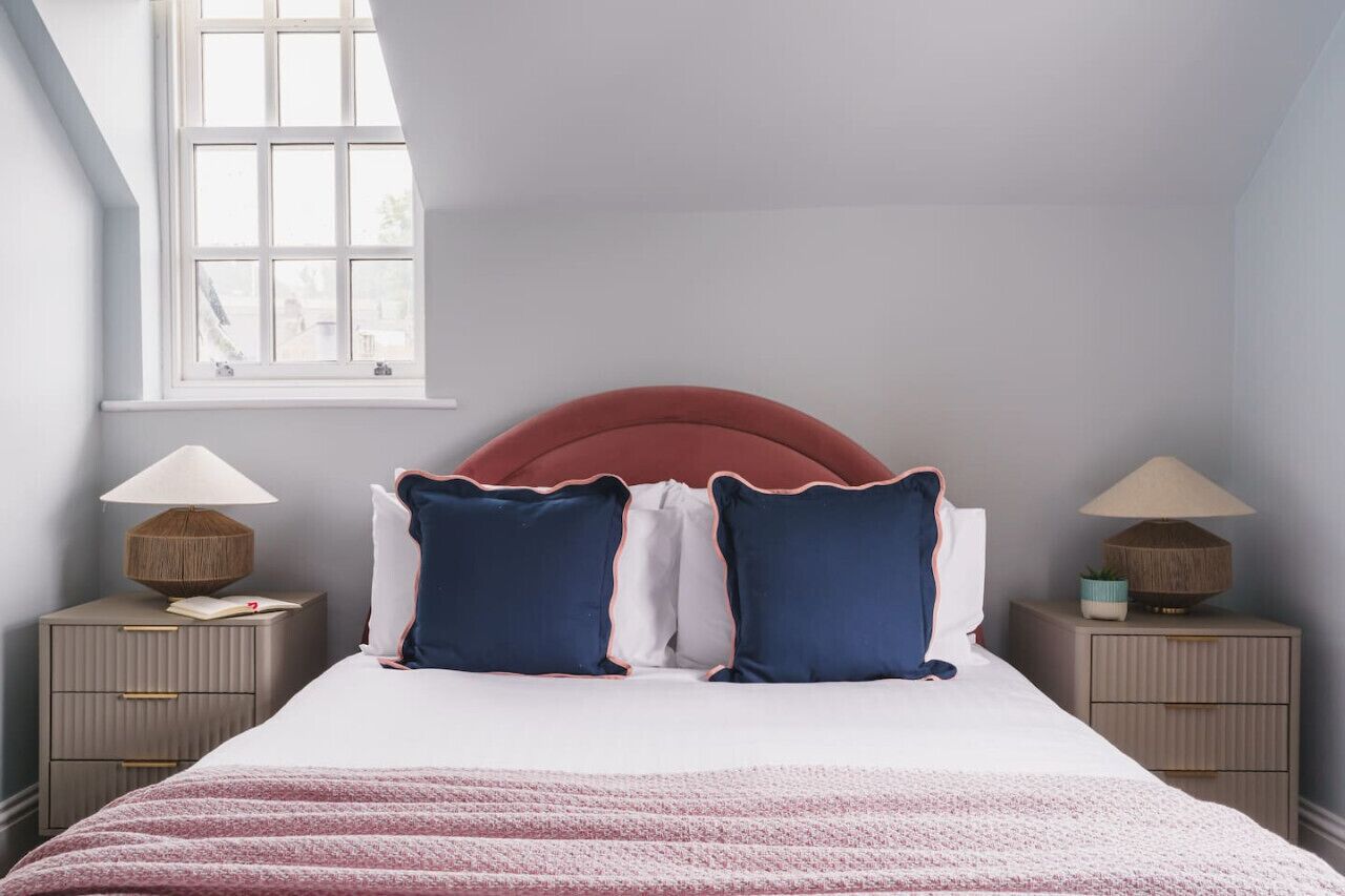 Ein ordentlich eingerichtetes Schlafzimmer mit einem Bett, zwei Nachttischen und einem Fenster.