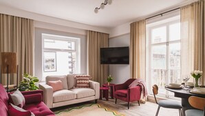 A modern living room with a sofa, armchair, and a dining area with a table and chairs. - Crescent Retreat- Windermere centre (Windermere)