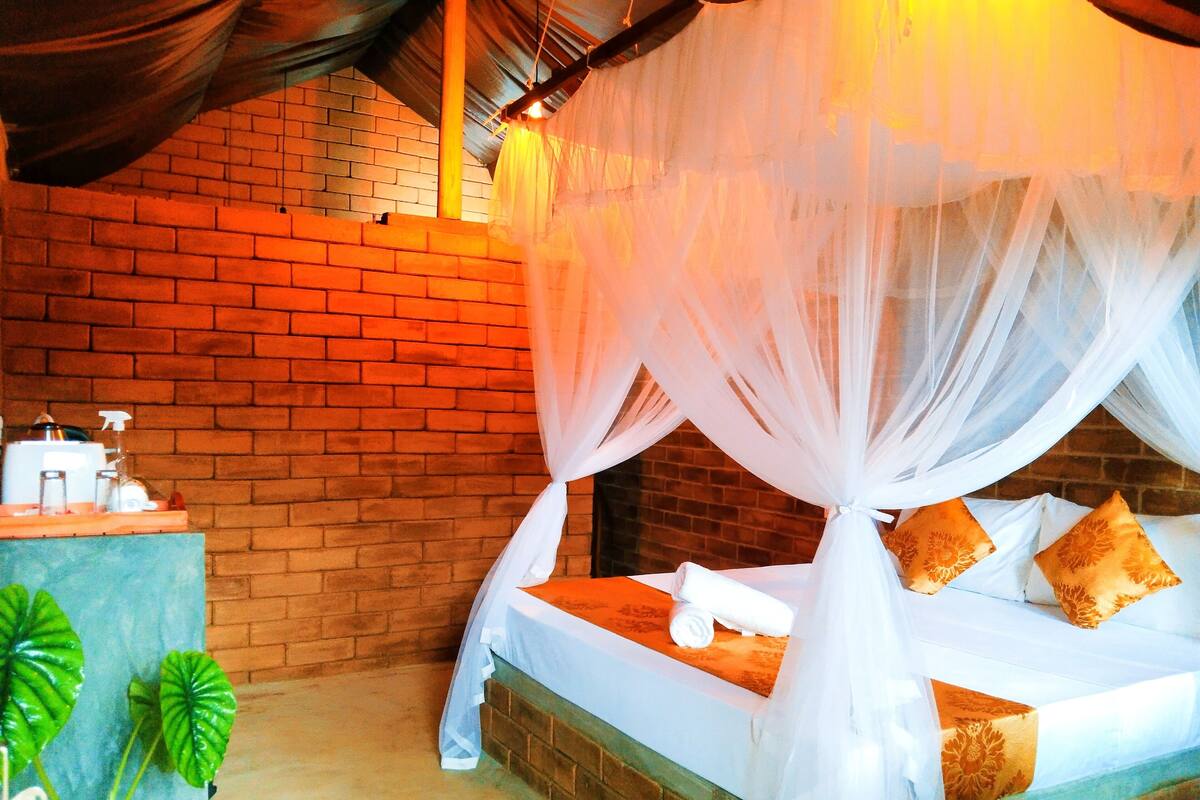 A bed with a white canopy, a brick wall, and a small table with toiletries.
