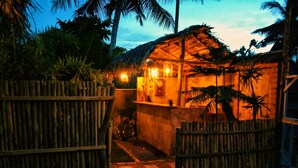 A thatched-roof structure with a wooden fence, surrounded by tropical vegetation. - LUNUVILA RESORT DICKWELLA (Dikwella)