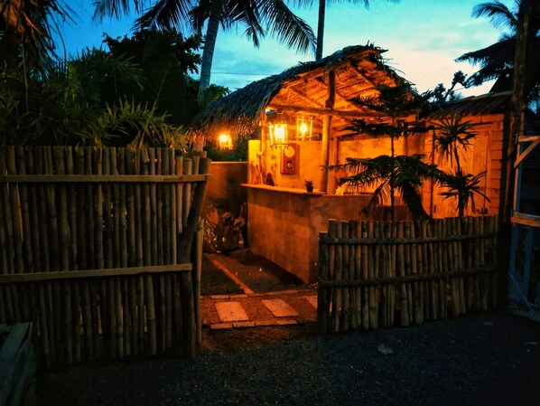 A thatched-roof structure with a wooden fence, surrounded by tropical vegetation. - LUNUVILA RESORT DICKWELLA (Dikwella)