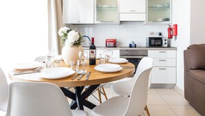 A modern kitchen with white cabinets, a dining table set for four, and a microwave. - Bright 2-bedroom Penthouse in Sliema, just steps from the promenade, Balluta beaches, cafés, and bus stops. Fully equipped with Wi-Fi, air conditioning, kitchen, and terrace — ideal for families or groups exploring Malta. (Tas-Sliema)