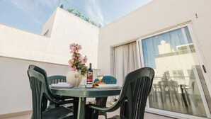 A balcony with a table set for two, featuring a bottle of wine, glasses, and a plate of food. - Bright 2-bedroom Penthouse in Sliema, just steps from the promenade, Balluta beaches, cafés, and bus stops. Fully equipped with Wi-Fi, air conditioning, kitchen, and terrace — ideal for families or groups exploring Malta. (Tas-Sliema)