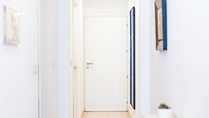 A hallway with a white door, a potted plant, and a framed picture on the wall. - Bright 2-bedroom Penthouse in Sliema, just steps from the promenade, Balluta beaches, cafés, and bus stops. Fully equipped with Wi-Fi, air conditioning, kitchen, and terrace — ideal for families or groups exploring Malta. (Tas-Sliema)